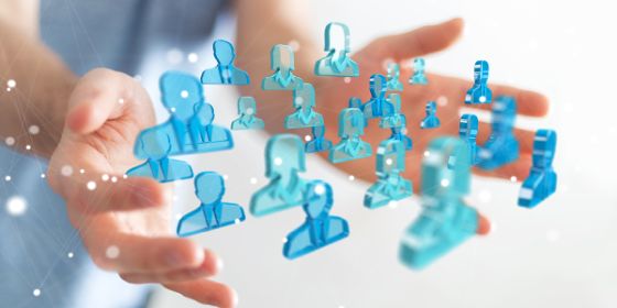 Foto de unas manos entre las que hay unos iconos que representan a personas conectadas