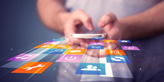 Foto de una persona utilizando su teléfono móvil del que salen multitud de iconos