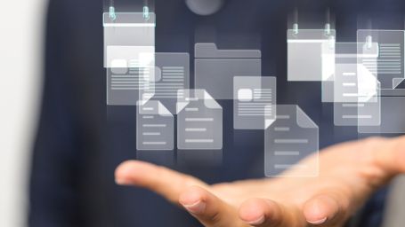 Imagen de una mano abierta hacia arriba con fichas de carpetillas difuminadas en suspensión por encima de esa mano