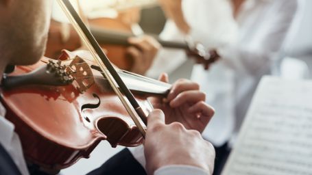 Fotografía de un músico tocando el violín en una orquesta
