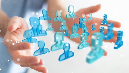 Foto de unas manos entre las que hay unos iconos que representan a personas conectadas