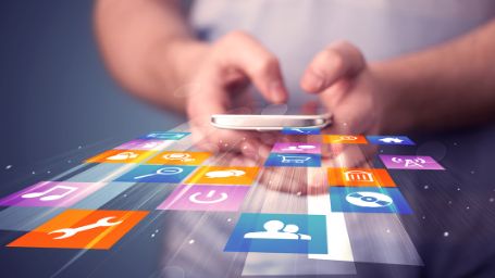 Foto de una persona utilizando su teléfono móvil del que salen multitud de iconos