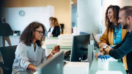 Empleada pública atendiendo en un mostrador a 2 personas 