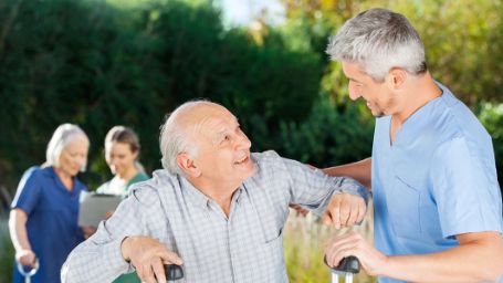 Hombre cuidando de un anciano con muletas