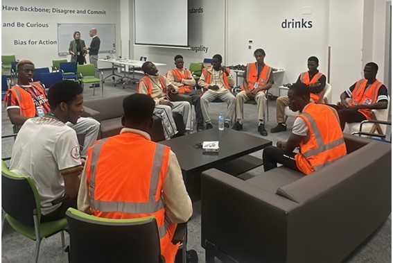 Imagen de un grupo de inmigrantes reunidos al rededor de una mesita, sentados en unos sofás y sillas