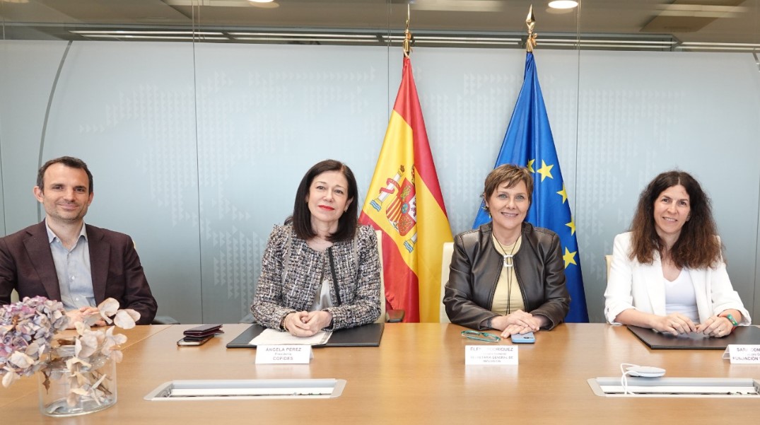 Sentadas detrás de un mesa se encuentran 4 personas (1 hombre a la izquierda y el resto mujeres). Detrás de ellos están las banderas de España y Europa.